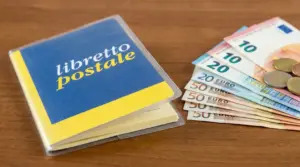 Libretto postale accanto a banconote e monete in euro su tavolo di legno