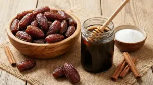 Datteri in una ciotola di legno accanto a sciroppo di datteri, zucchero e cannella su un tavolo rustico