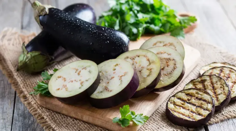 Fette di melanzana crude e grigliate su un tagliere con prezzemolo fresco